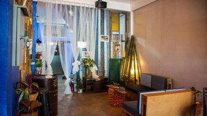 A cozy room with a wooden bench, a small table, and potted plants. - TT Hostel (Vientiane)