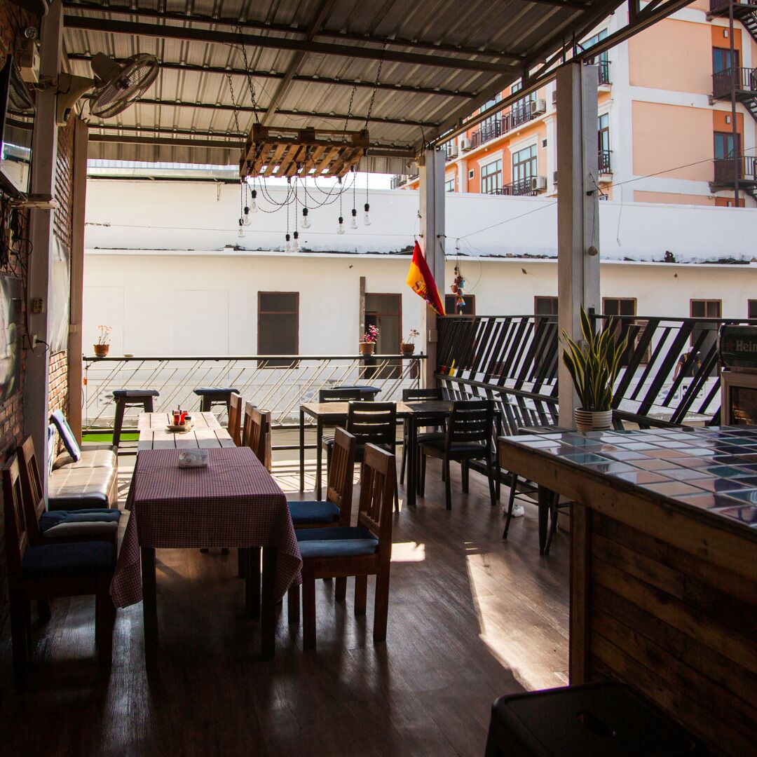 An outdoor patio area with wooden tables and chairs, a checkered tablecloth, and a flag.