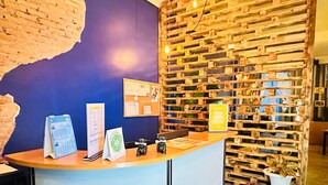 A reception desk with a blue wall, wooden panel wall, and a bulletin board. - TT Hostel (Vientiane)