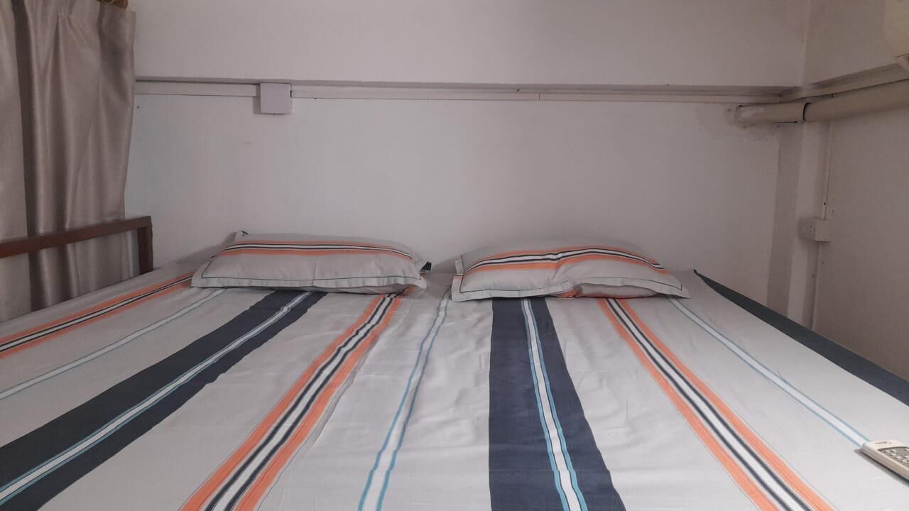 A twin bed with striped bedding and two pillows.