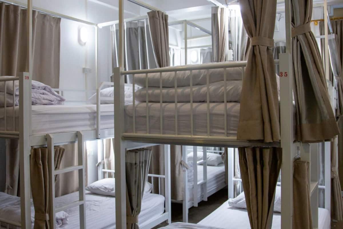 A dormitory-style room with bunk beds, curtains, and a number on the wall.