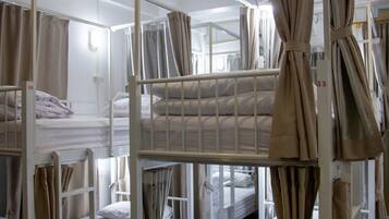 A dormitory-style room with bunk beds, curtains, and a number on the wall.