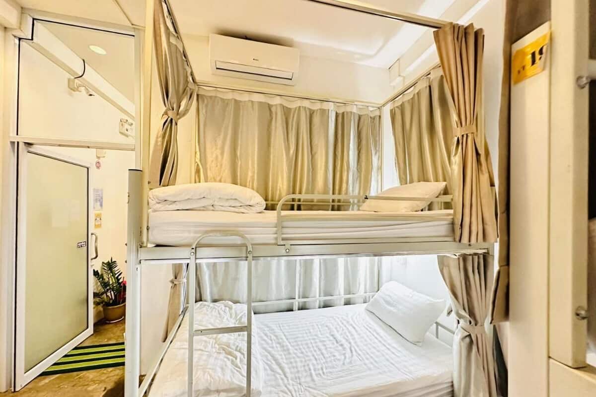A bunk bed room with curtains, a door, and an air conditioning unit.