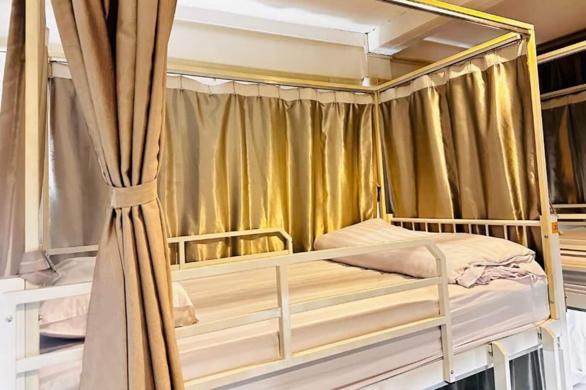 A bunk bed with a canopy, white metal frame, and beige bedding.