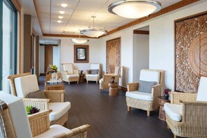 A spacious lobby with wicker furniture, a large decorative wall, and a ceiling with recessed lighting.