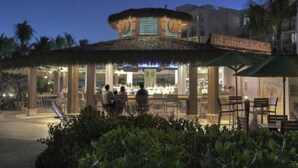 Un restaurante con techo de paja y mesas al aire libre.