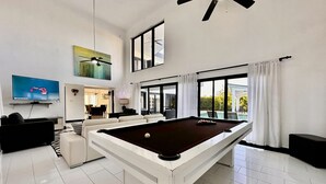 A modern living room with a pool table, a flat-screen TV, and a ceiling fan. - CASA COCO-ELROY Oceanview, Premium 4 Bedroom @ Casa Linda (Sosúa)