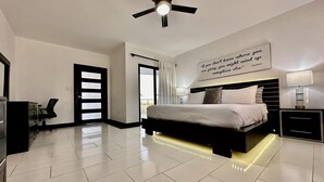 Un dormitorio moderno con una cama, un ventilador de techo, un escritorio y una silla.