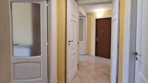 Un pasillo con puertas blancas, paredes amarillas y suelo de baldosas.