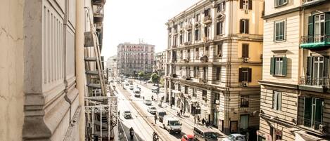 A street view with multi-story buildings, a busy road, and a clear sky.