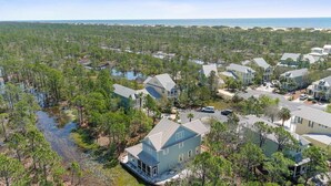 A coastal residential area with houses surrounded by dense forest and a beach in the background. - Avalon - 3BR/3BA beach house with beach view (Gulf Shores)