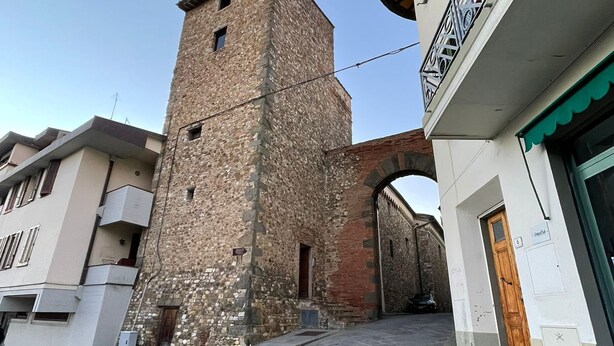 A narrow stone-paved street with a historic stone tower and modern buildings. - Characteristic apartment in historic 1300s tower (San Casciano in Val di Pesa)