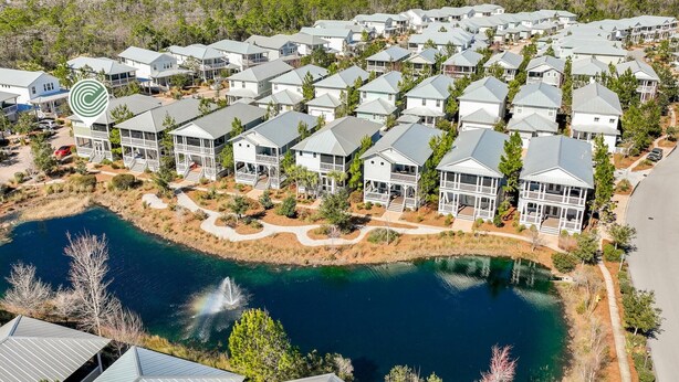 Uma área residencial com várias casas, um espelho d'água central e paisagismo bem cuidado.