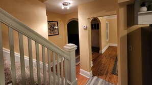 A hallway with a wooden staircase, a ceiling light, and a framed quote on the wall. - Huge deck & yard Near Indoor Sports Arena! Spacious! Smart TVs! Fast Wifi! Cozy. (Machesney Park)