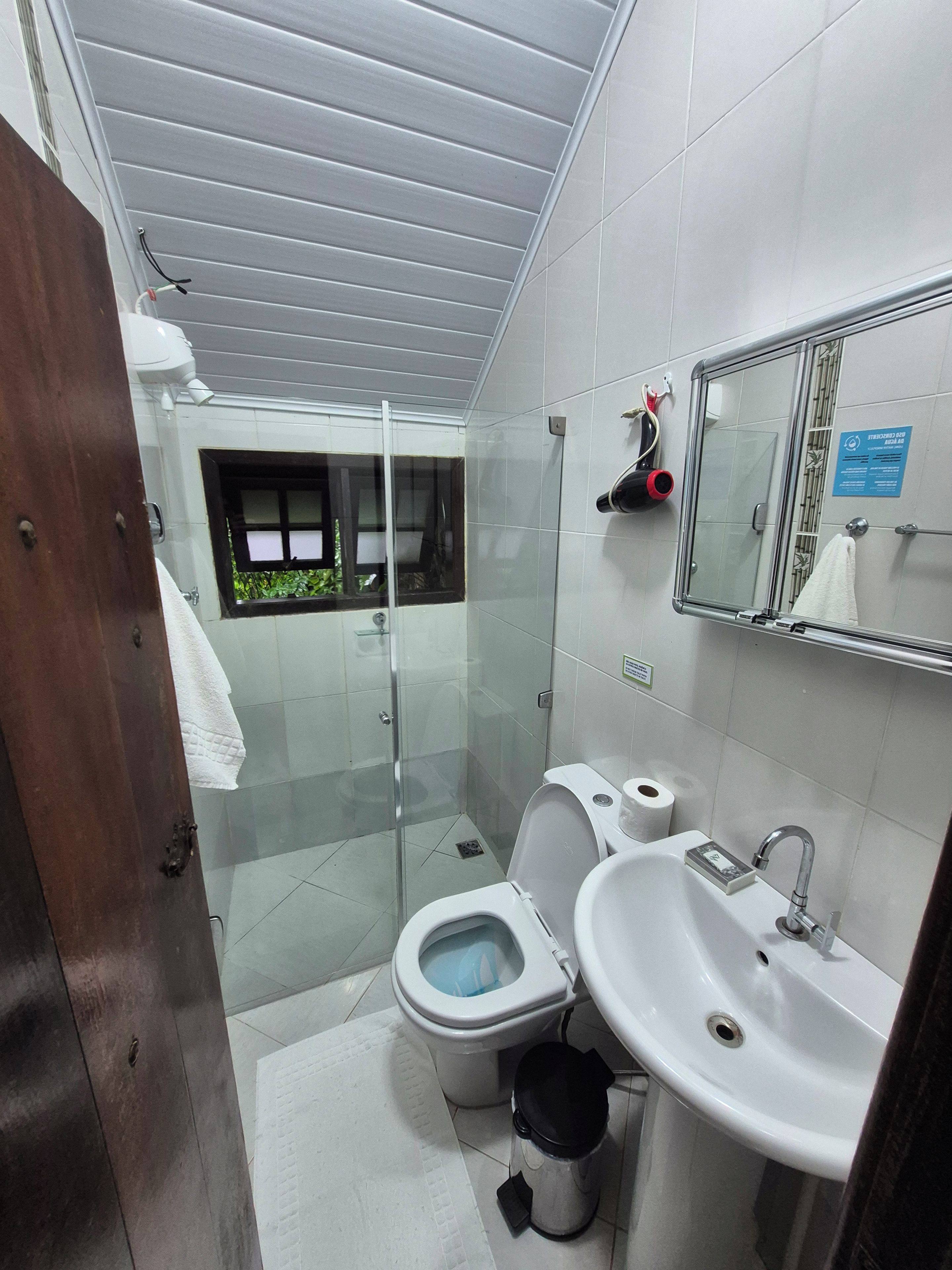 Ein modernes Badezimmer mit Toilette, Waschbecken und einer Dusche mit Glastrennwand.