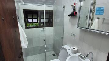 Ein modernes Badezimmer mit Toilette, Waschbecken und einer Dusche mit Glastrennwand.