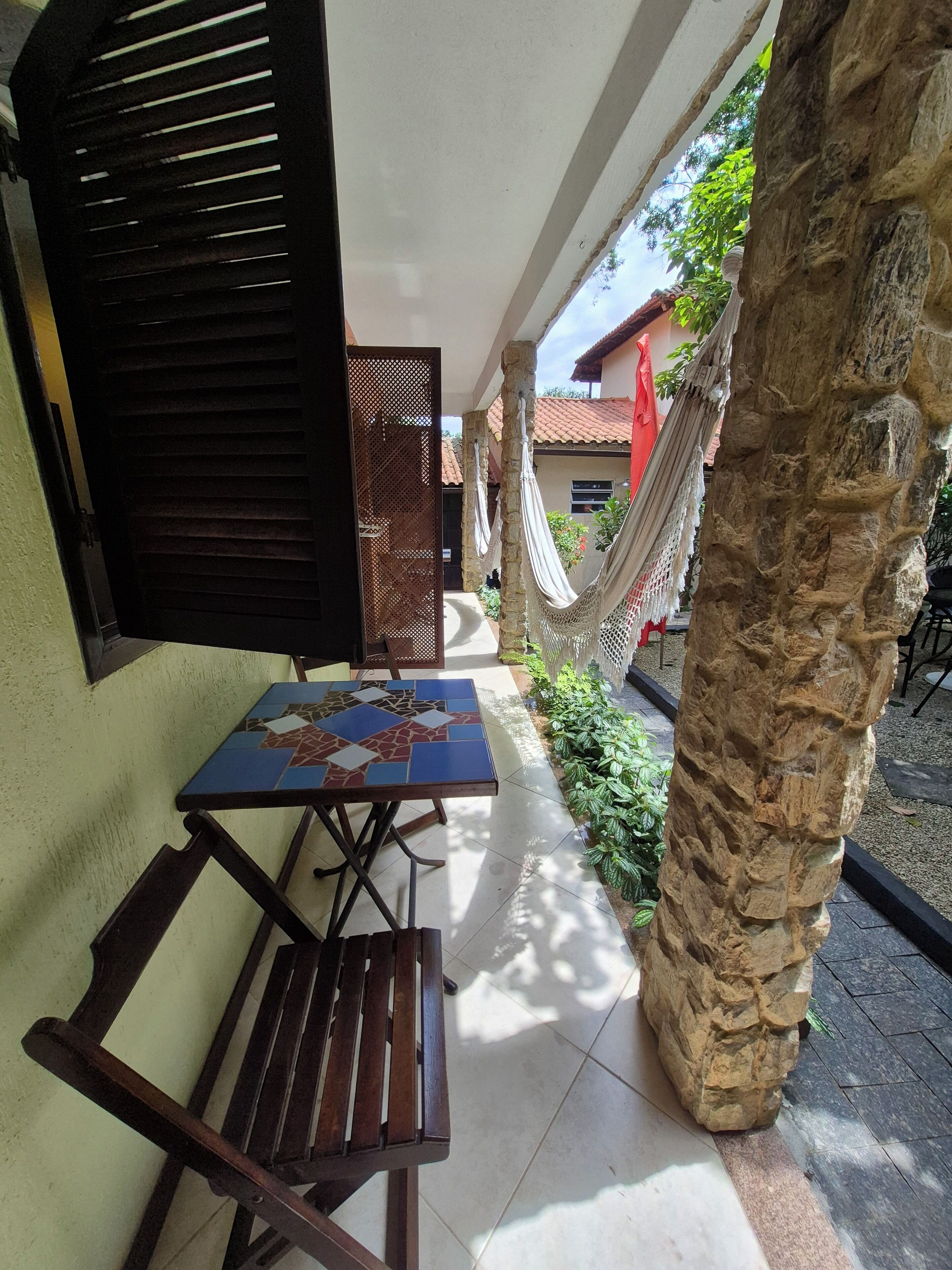 Une terrasse extérieure avec une table et des chaises, un hamac et un pilier en pierre.