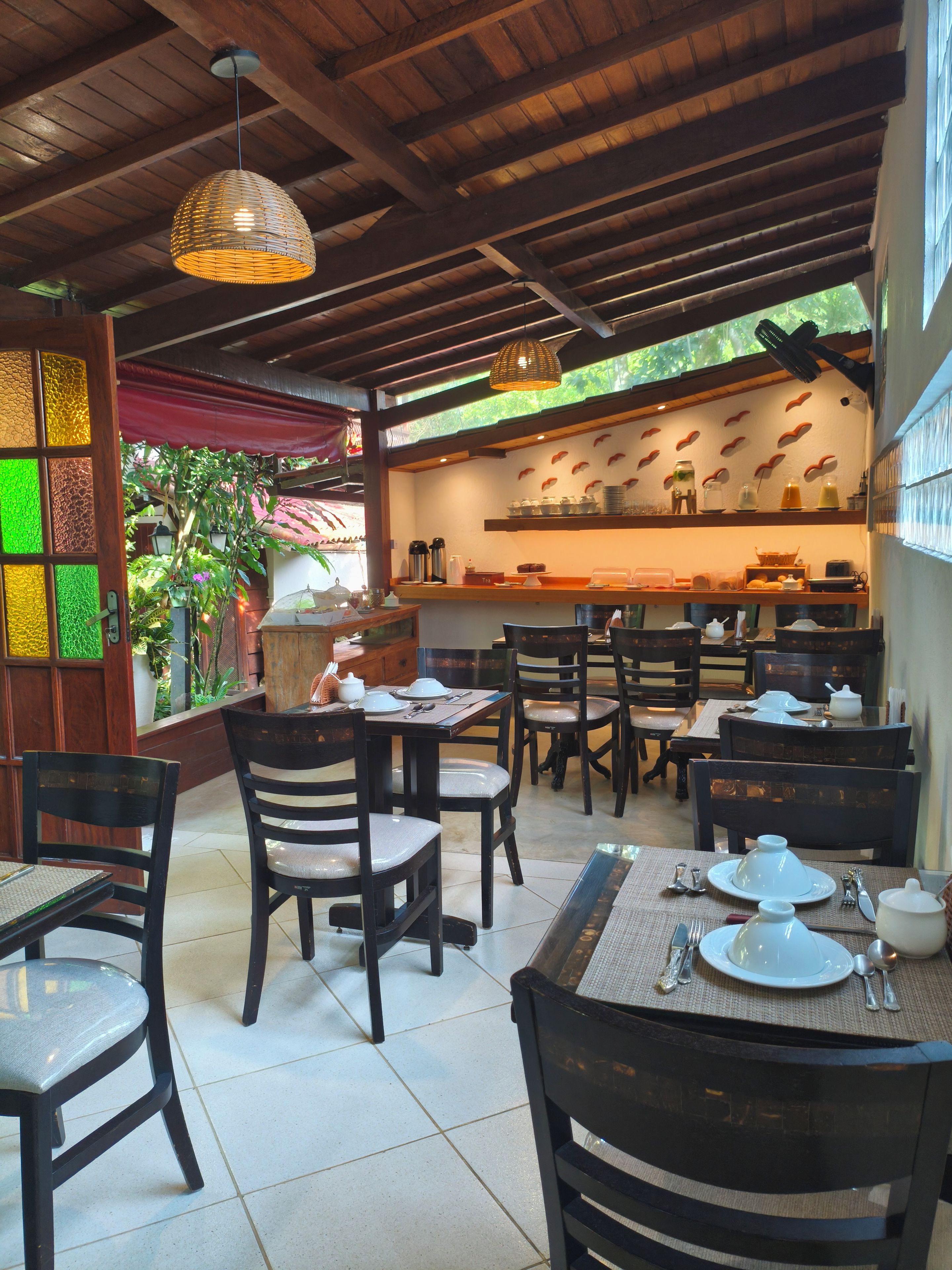 A restaurant with wooden furniture, a tiled floor, and a kitchen area with shelves.