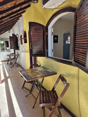 A covered outdoor seating area with wooden furniture and a tiled floor. - Aratinga inn (Angra dos Reis)