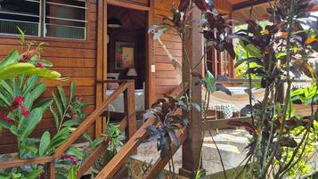 A wooden house with a porch, a staircase, and various plants.