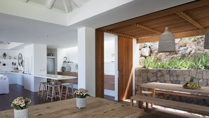 Eine moderne Küche mit weißen Schränken und einem Essbereich mit Holzboden vor einer Wand aus Stein.