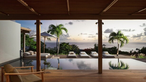 Ein Poolbereich mit Liegestühlen und Blick aufs Meer.