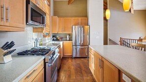 Eine moderne Küche mit Holzschränken, Edelstahlgeräten und Holzboden.