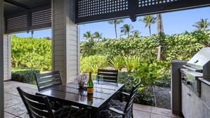 An outdoor patio with a table set for two, a grill, and lush greenery in the background. - Private Mauna Lani Residence with Pool (Kamuela)