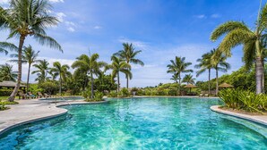 A clear blue pool surrounded by palm trees and lounge chairs.
