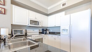 Una cocina moderna con armarios blancos, electrodomésticos de acero inoxidable y encimeras de granito.