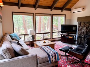 A living room with a sofa, a coffee table, a TV, and a fireplace. - Cute & Cozy Cabin in Black Butte Ranch (Black Butte Ranch)