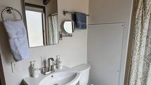 Un baño con lavamanos, espejo, inodoro y cortina de ducha.