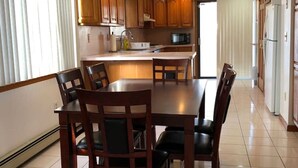 Una cocina amplia con armarios de madera, una isla central y un comedor con sillas.