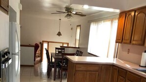 Una cocina amplia con armarios de madera, un comedor con sillas y un ventilador de techo.