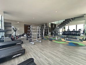 Un gimnasio moderno con cintas de correr, máquinas de pesas y pesas sueltas.