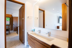 A modern bathroom with a large mirror, dual sinks, and wooden cabinetry.