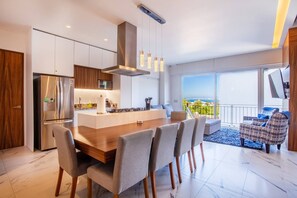 Een moderne keuken met een centraal eiland, roestvrijstalen apparatuur en hanglampen.
