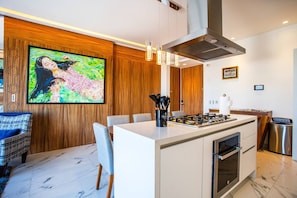 Una cocina moderna con una isla central, paneles de madera y un cuadro grande.