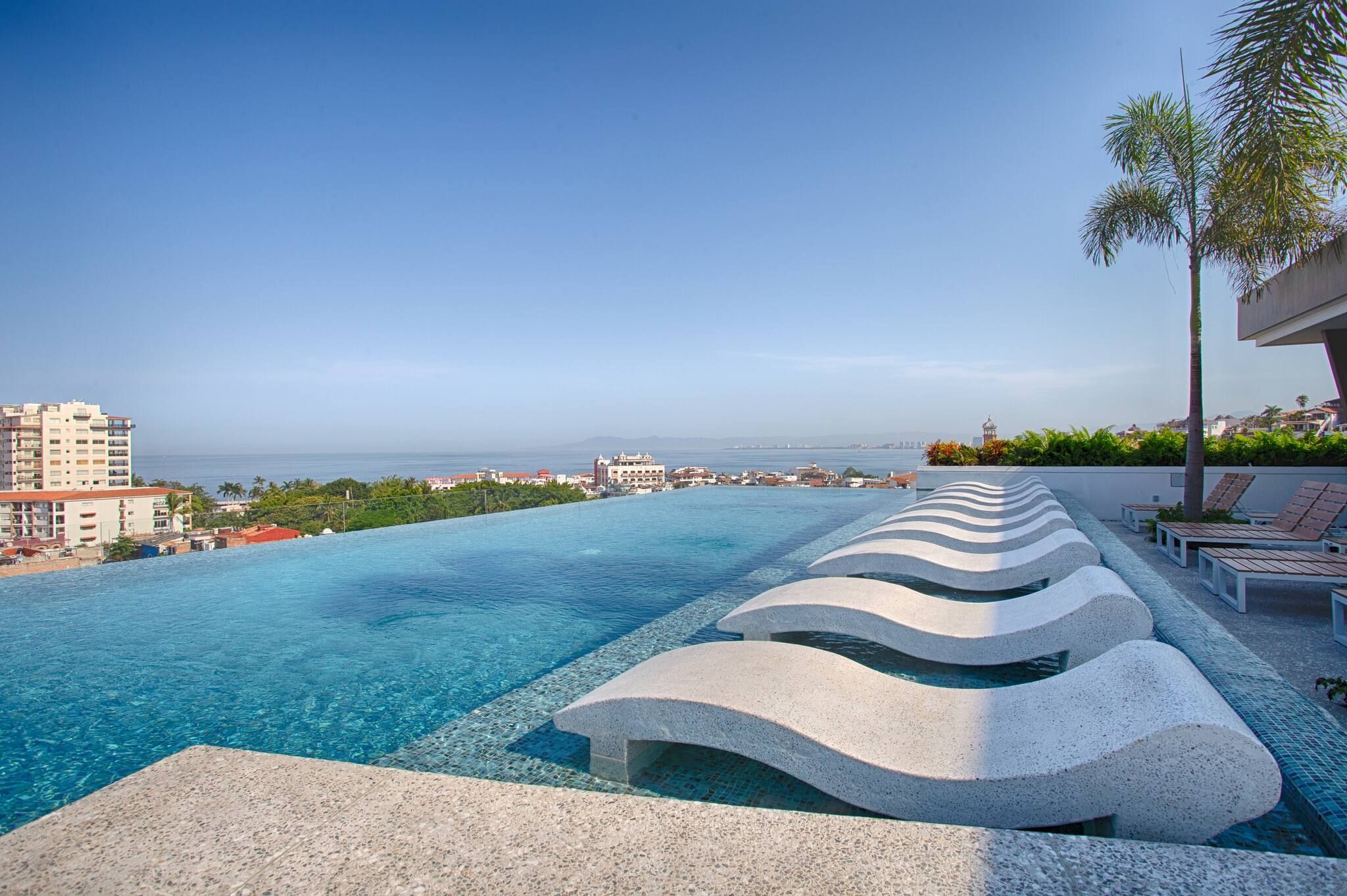 Una piscina con vista al mar y edificios al fondo.