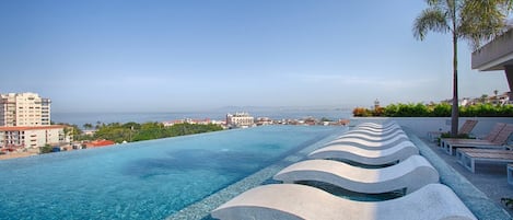 Una piscina con vista al mar y edificios al fondo.