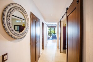 A hallway with wooden doors, a large decorative mirror, and a view of a balcony with outdoor furniture.