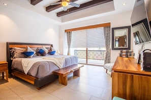 A bedroom with a large bed, a wooden bench, a desk, and a balcony with a view. - Workspace, Mini-Bar & Rooftop Pool | 2BR Retreat (Puerto Vallarta)