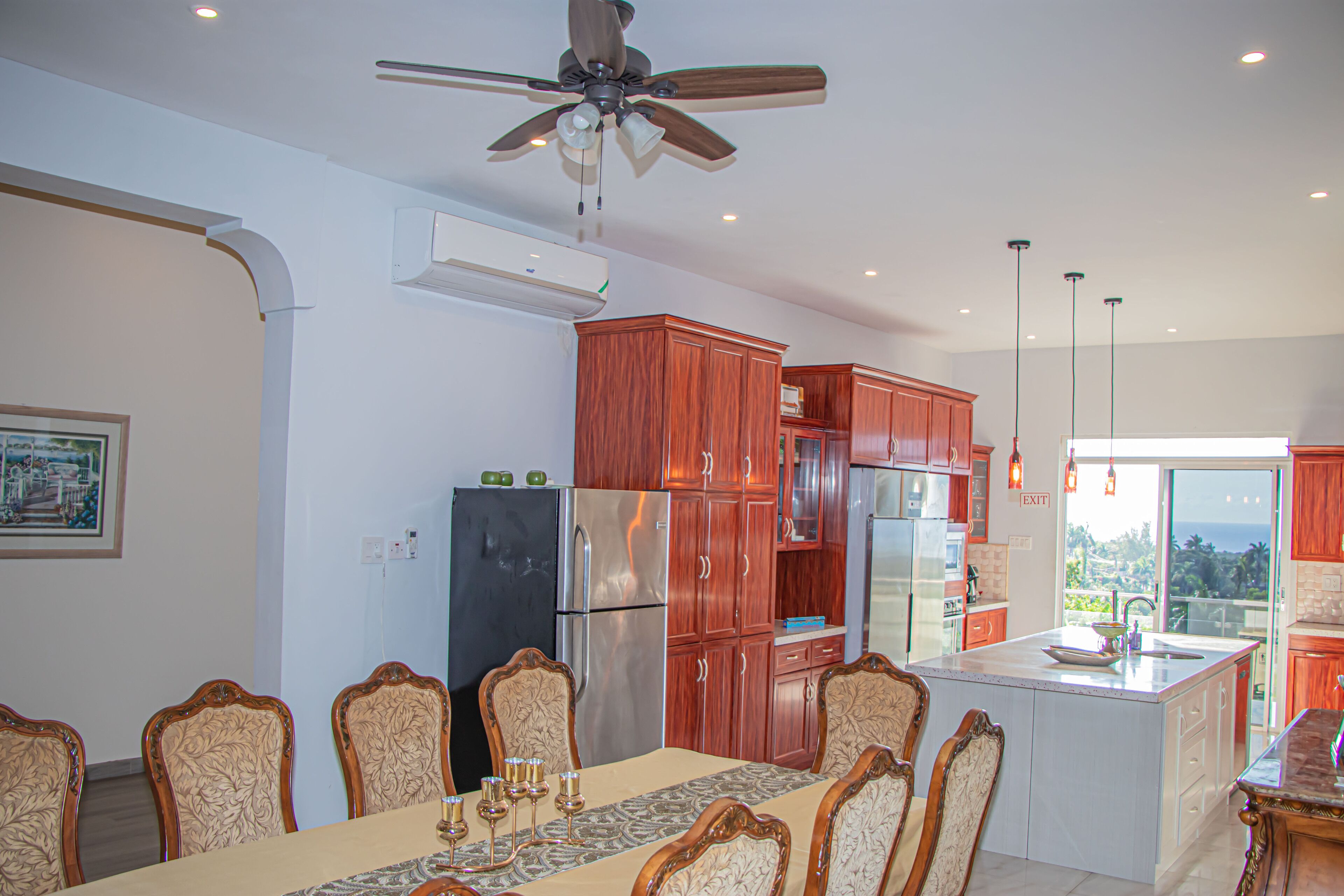 A modern kitchen with wooden cabinets, a stainless steel refrigerator, and a dining area with a table and chairs.