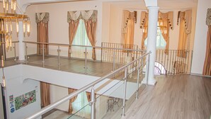 Um interior espaçoso com teto alto, guarda-corpo de vidro no andar superior e escadaria descendo.
