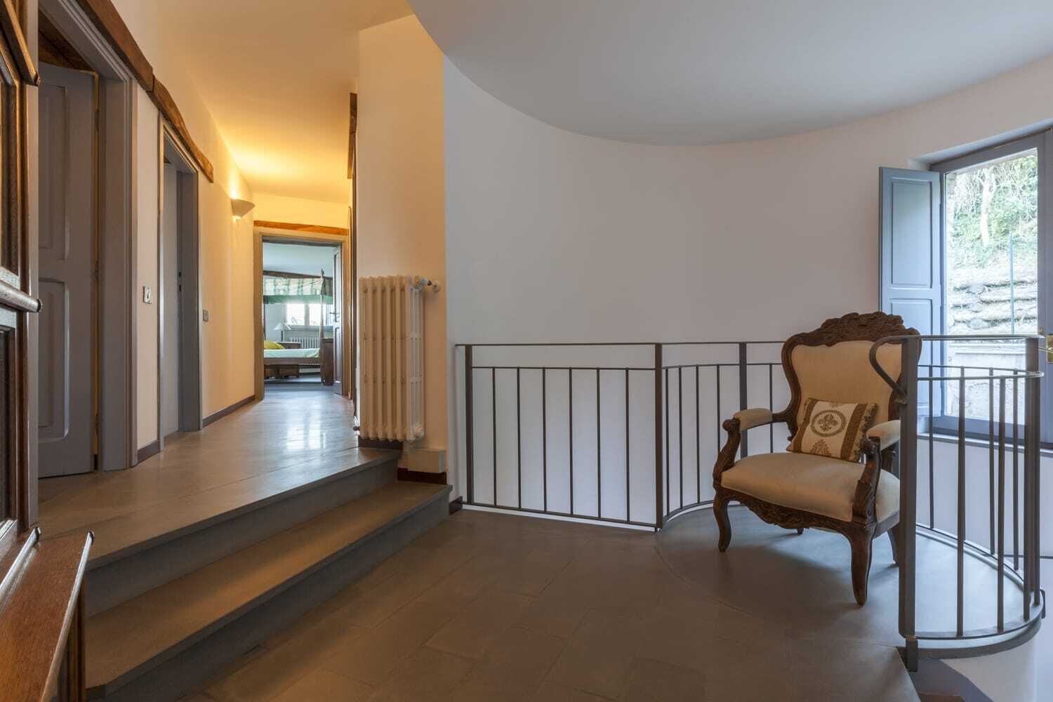 Un escalier menant à un balcon où se trouve une chaise.
