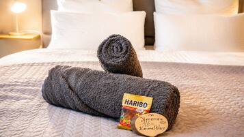 Ein ordentlich bezogenes Bett mit einem gerollten Handtuch und einer Haribo-Riegel.