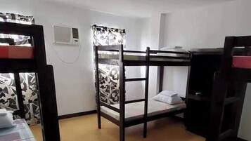 A room with bunk beds, a desk, and a chair.