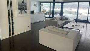 Ein modernes Wohnzimmer mit großem Fenster, einer Couch und einem Essbereich.