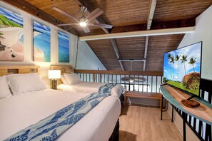 Une chambre d’hôtel avec deux lits, un ventilateur de plafond, une télévision et des œuvres d’art représentant des scènes tropicales.