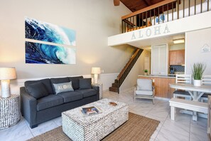 A living room with a grey sofa, a coffee table, and a staircase leading to an upper level.